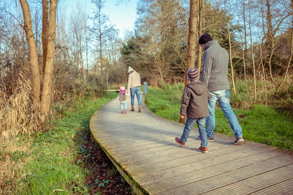 Gezin wandelt over een knuppelbrug in Hart van Limburg tijdens de winter