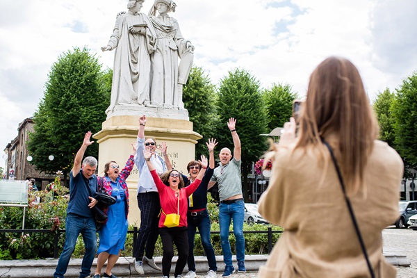 Groep bezoekers poseert voor het standbeeld op de Markt in Maaseik, vlakbij het kantoor van Visit Maaseik