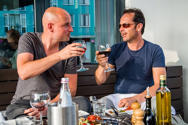 Zwei Männer stoßen auf einer Terrasse in Heythuysen mal Preuf Heytse an